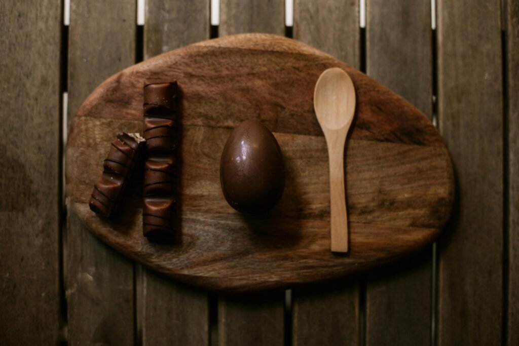 Flat lay composition of chocolate egg and wooden spoon on a rustic tray.