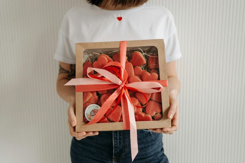 Box of heart-shaped cookies tied with a pink ribbon, perfect gift idea.